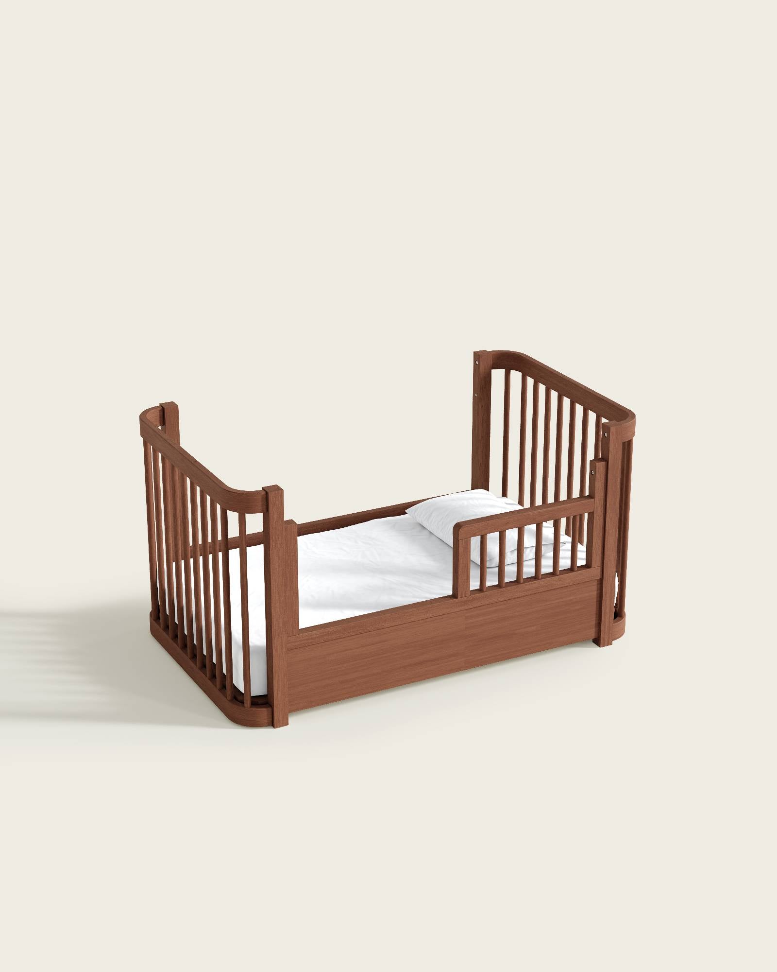 Brown wooden baby crib with slatted sides and mattress, viewed from the side.