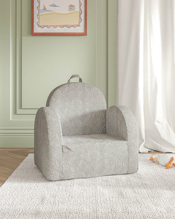 A child's armchair on a rug in a room with green walls