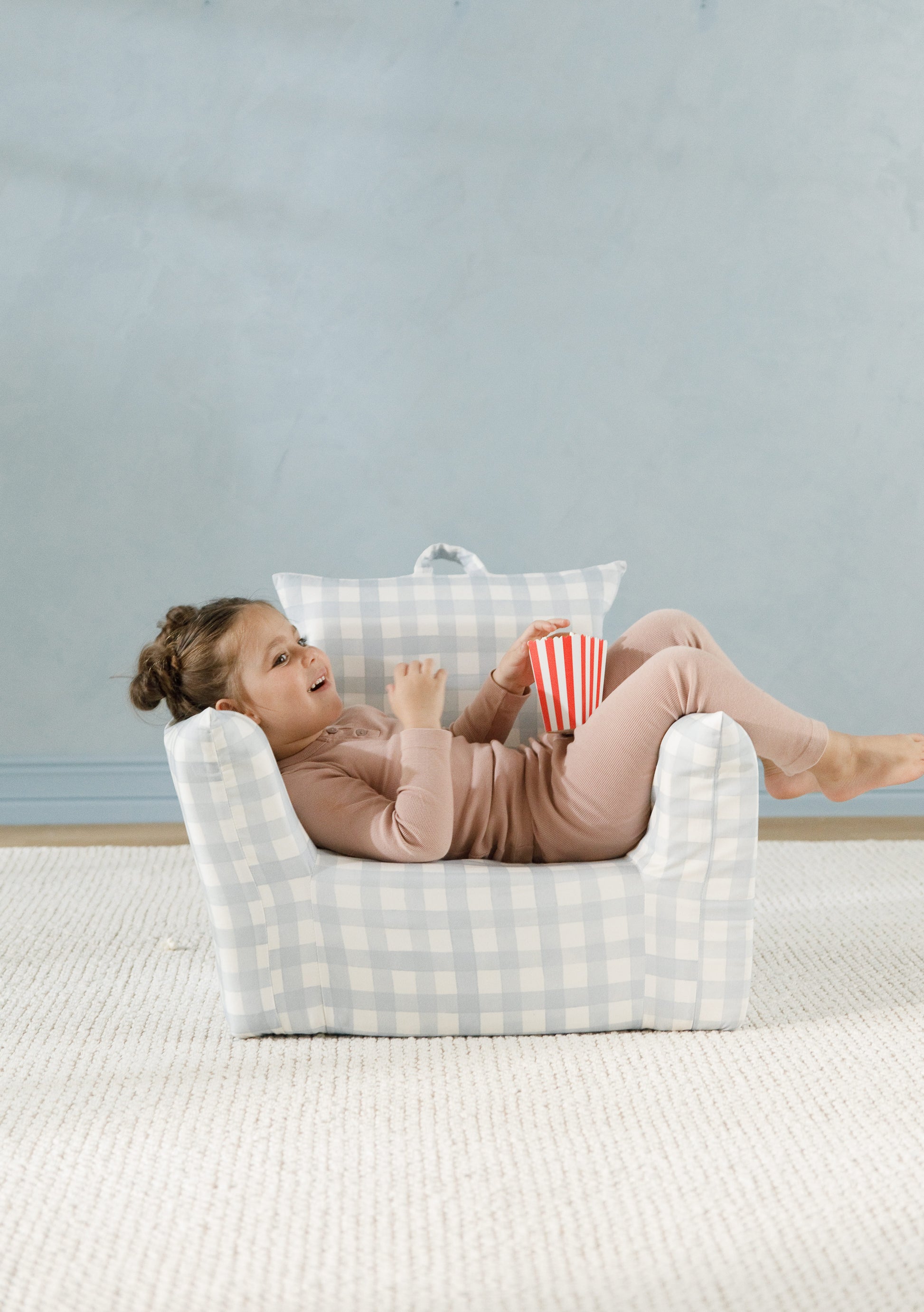 Small armchair with a white fabric featuring colorful animal and nature-themed illustrations, in a room with yellow walls.